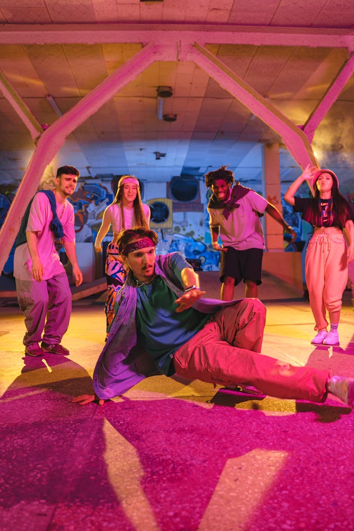 Group of diverse young adults breakdancing in a vibrant neon-lit warehouse.