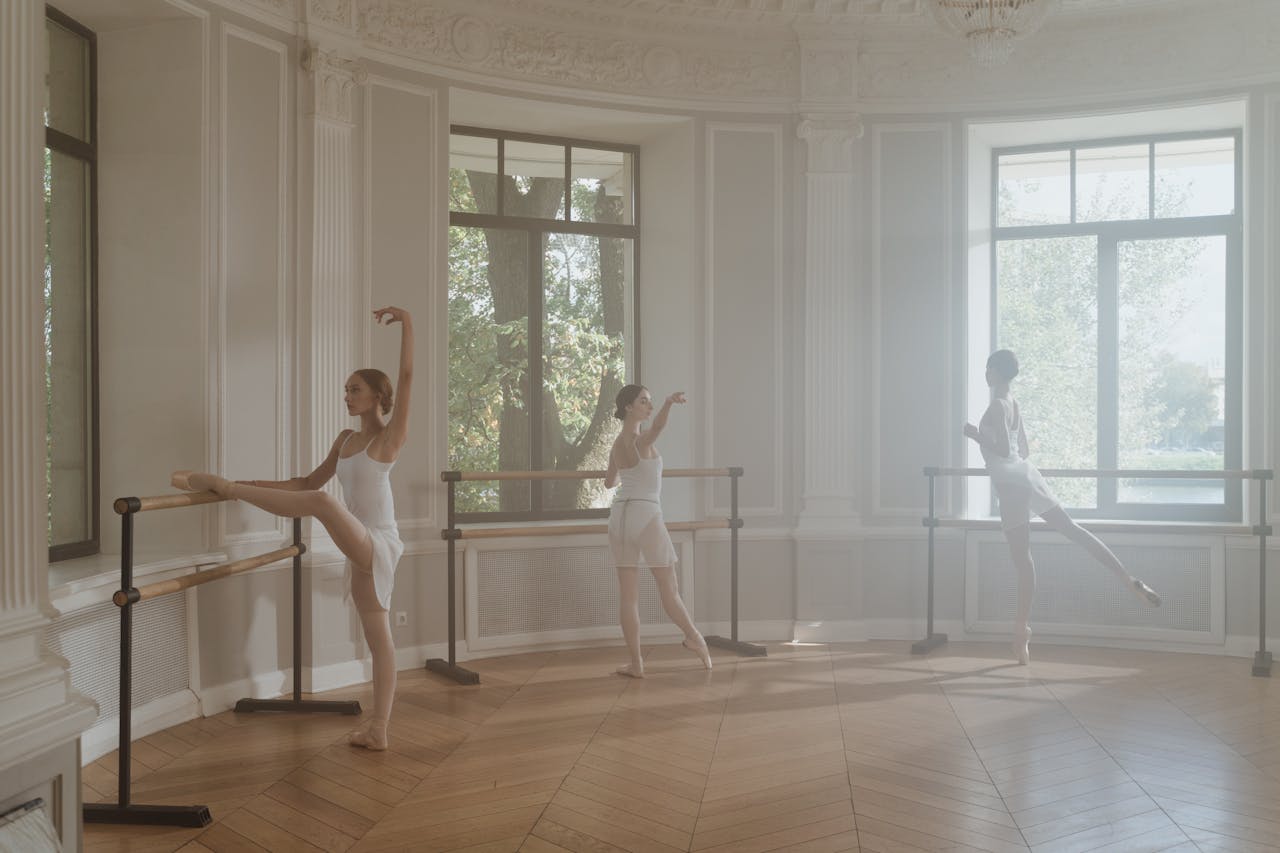 Young ballet dancers practicing at the barre in an elegant, sunlit studio.